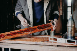 hombre barnizando moldura de madera