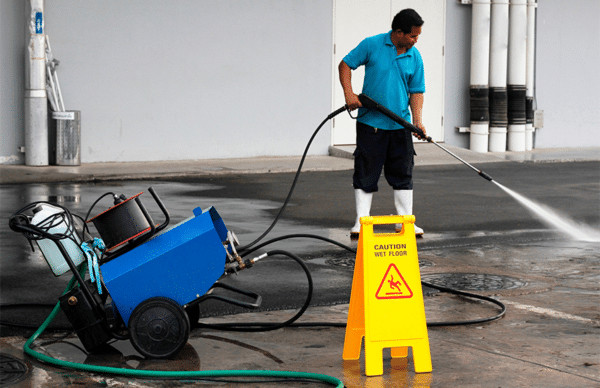hombre con maquina de lavado a presión limpiando suelo de cemento