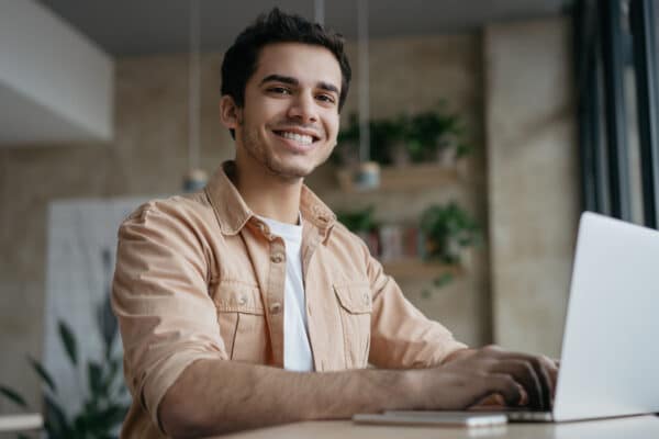 Hombre sonriente trabajando delante de portátil