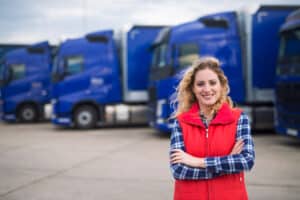 mujer sonriente delante de flota de camiones
